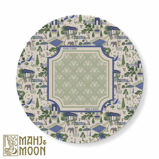 Round American Mahjong mat featuring a blue and sage green garden toile design with pavilions, peacocks, elephants, fountains and botanical motifs surrounding a soft green central playing area.